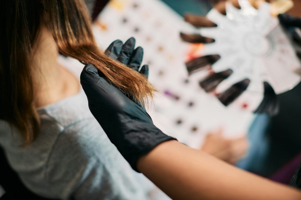 Close-up of hairdresser choosing hair color during treatment at the salon.