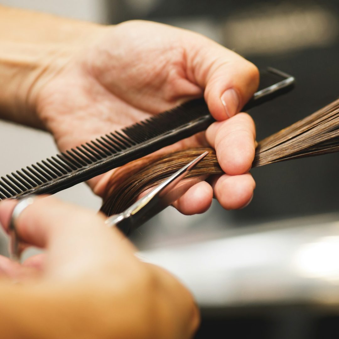 Hairdresser male hands during cutting female hair